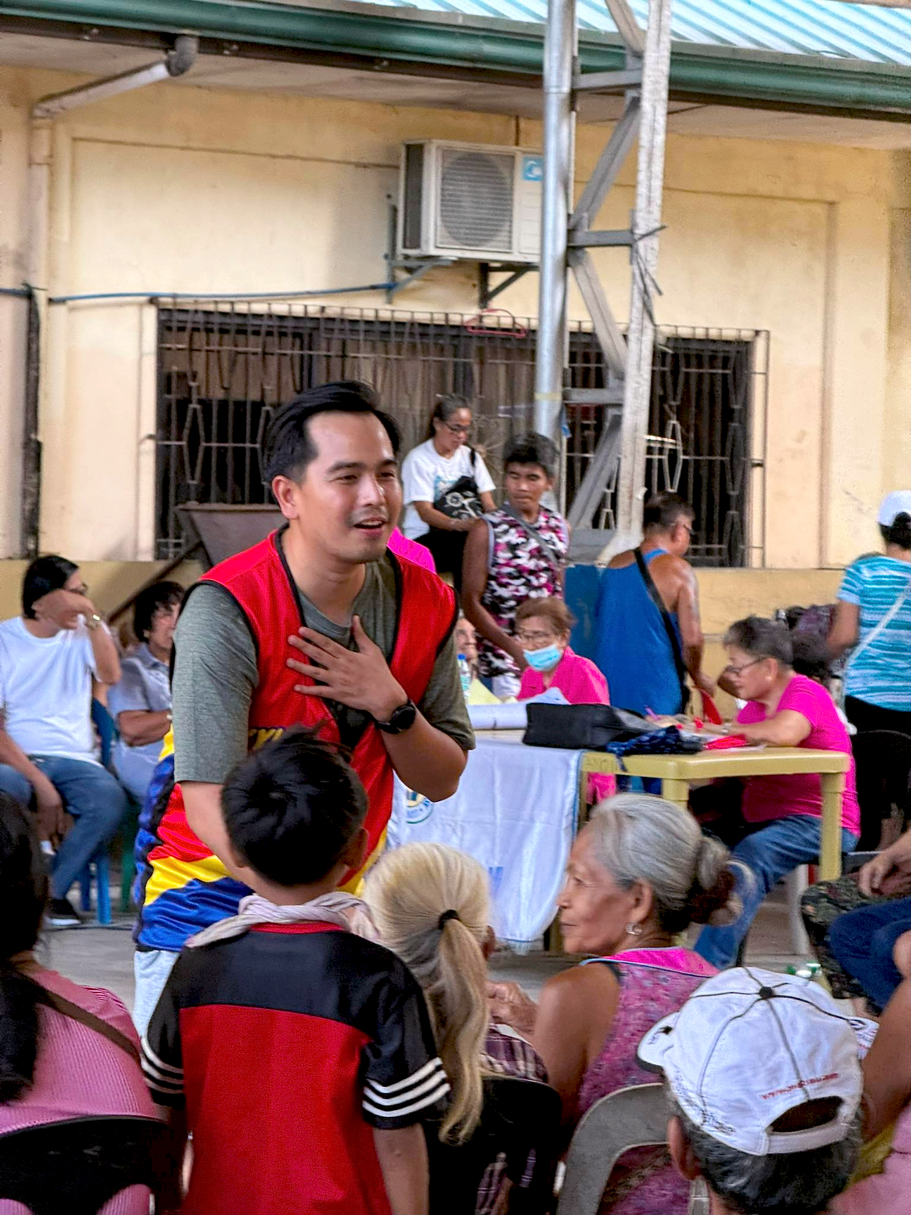 Councilor Kyle Nisce, hand on heart, smiling with residents at a community gathering in San Fernando, La Union